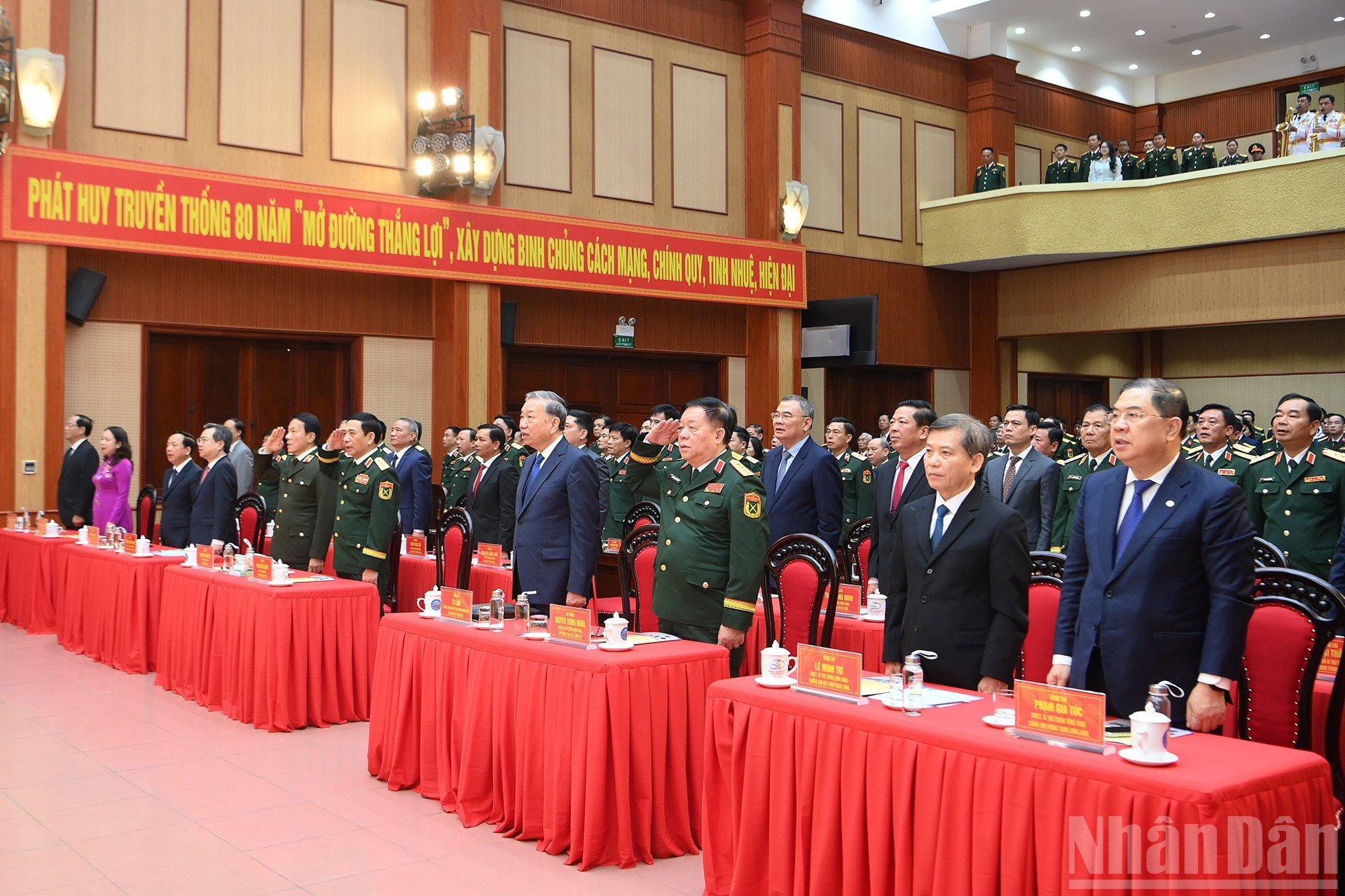 To Lam y los delegados realizan el saludo a la bandera nacional en la ceremonia.