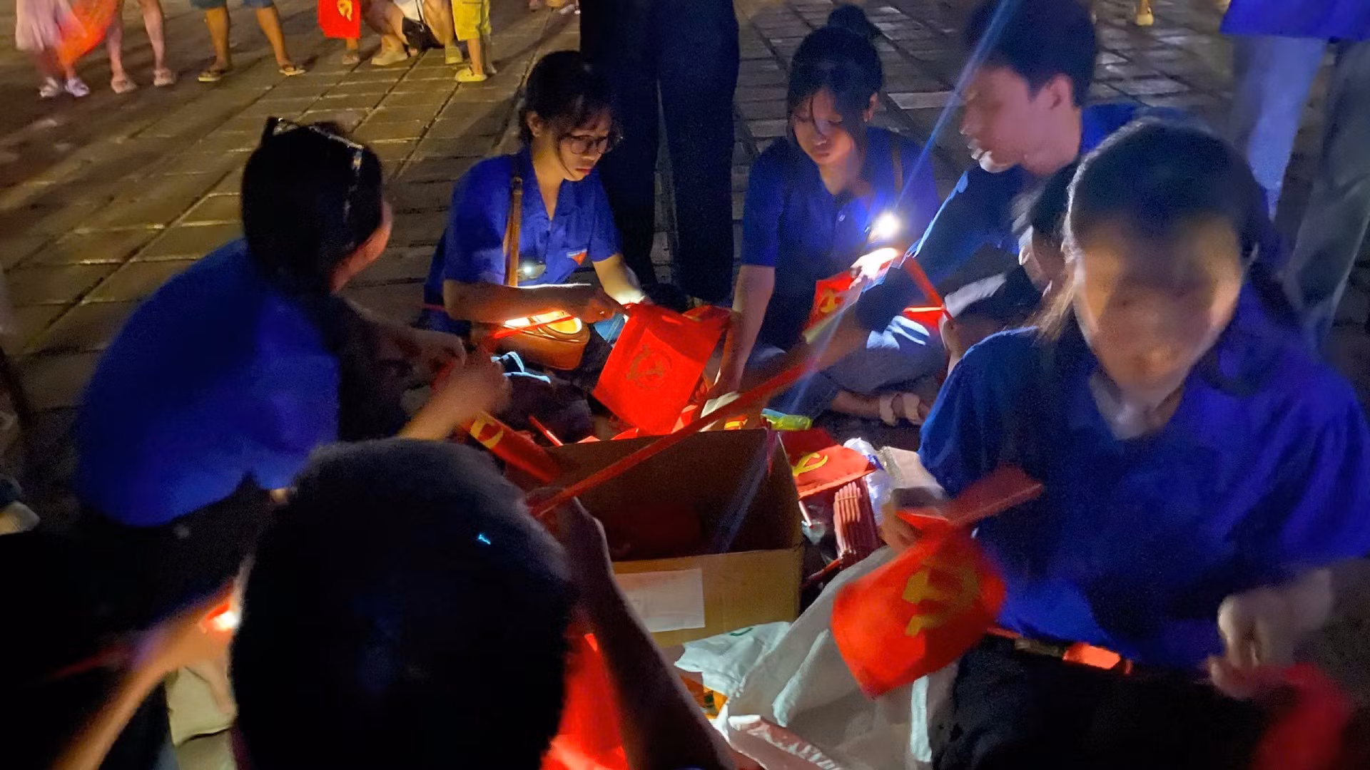 El rojo de la bandera nacional se destaca entre las luces del escenario, creando un mar de colores resplandecientes.