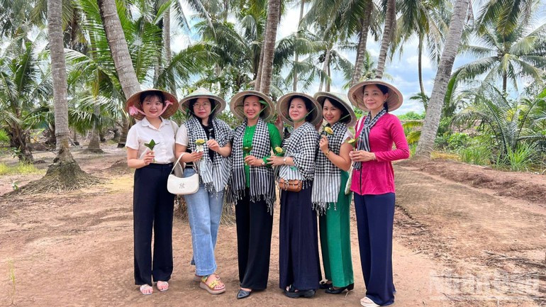 Los visitantes se toman fotografías de recuerdo junto a los cocoteros.