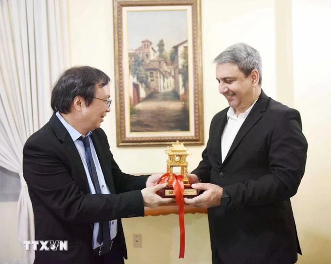 El presidente de la junta directiva y director general de la Editorial de Educación de Vietnam, Nguyen Tien Thanh (izquierda), entrega un recuerdo al ministro cubano de Educación Superior, Walter Baluja García. (Foto: VNA)