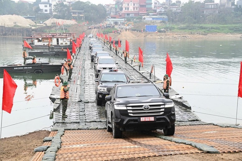 Personas y vehículos circulan con normalidad a través del puente flotante sobre el río Lo en la mañana del 16 de febrero. (Foto: qdnd.vn)