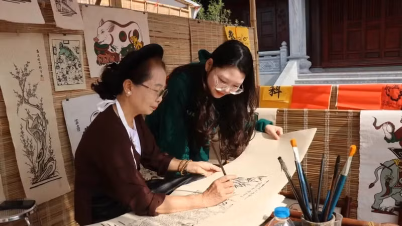 Los visitantes descubren el proceso de elaboración de la pintura popular de Dong Ho. (Foto: VNA)