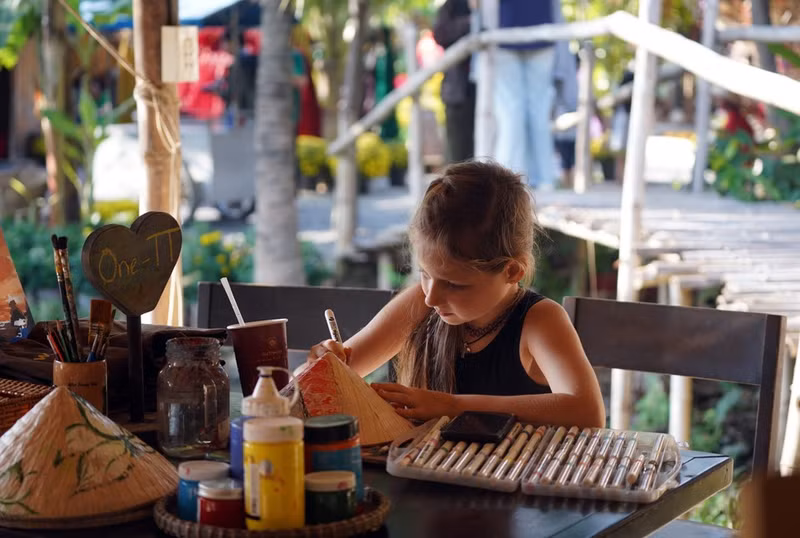 Niños extranjeros escriben caligrafía en un espacio dedicado a las tradicionales celebraciones del Tet en el pasado.