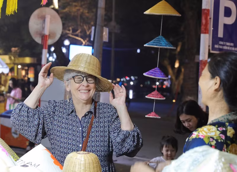 Visitantes internacionales disfrutan de productos tradicionales vietnamitas en el Festival de Regalos Turísticos de Hanói 2025.