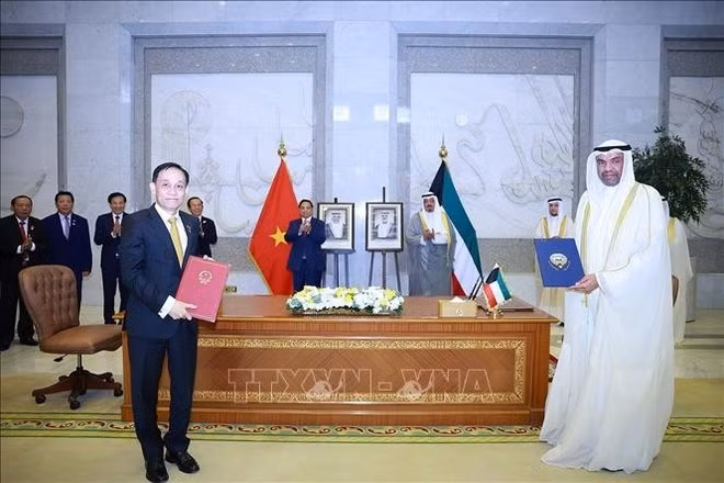 Los dos primeros mnistros presencian la ceremonia de firma del Protocolo que modifica el Acuerdo de Exención de Visado para Pasaportes Diplomáticos y Oficiales y el Memorando de Entendimiento entre la Academia Diplomática de Vietnam y el Instituto Diplomático Saud Al-Nasswe Al-Sabah de Kuwait. (Foto: VNA)