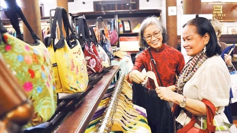 Turistas compran productos en una tienda de productos de la aldea de Van Phuc. (Foto: Nhan Dan)