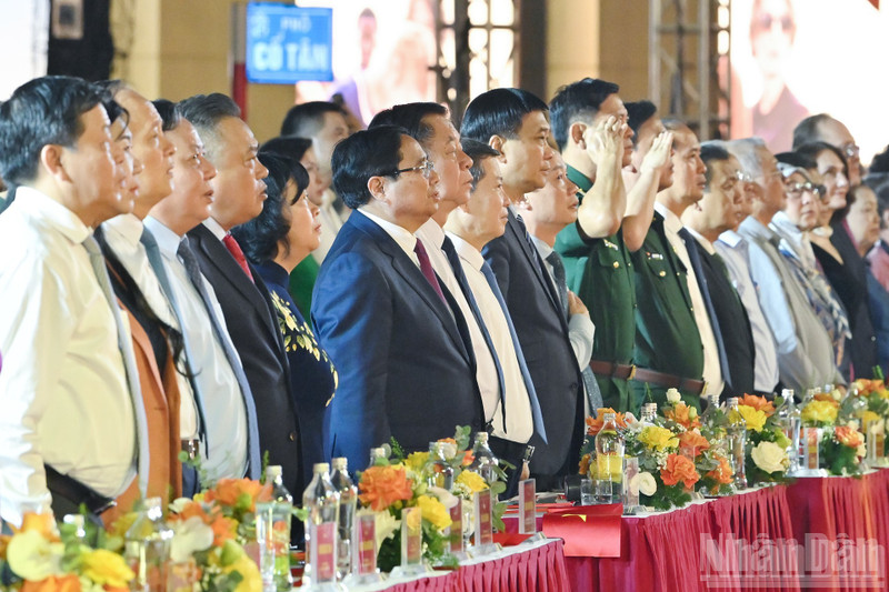 Los delegados saludan a la bandera nacional en el programa. (Foto: Nhan Dan)