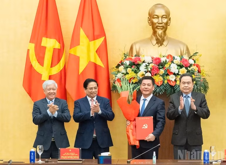 El primer ministro Pham Minh Chinh (segundo desde la izquierda) y el presidente de la Asamblea Nacional Tran Thanh Man (extrema derecha), entregan la decisión del nombramiento y ofrecen flores a Nguyen Hong Dien. (Foto: Nhan Dan)