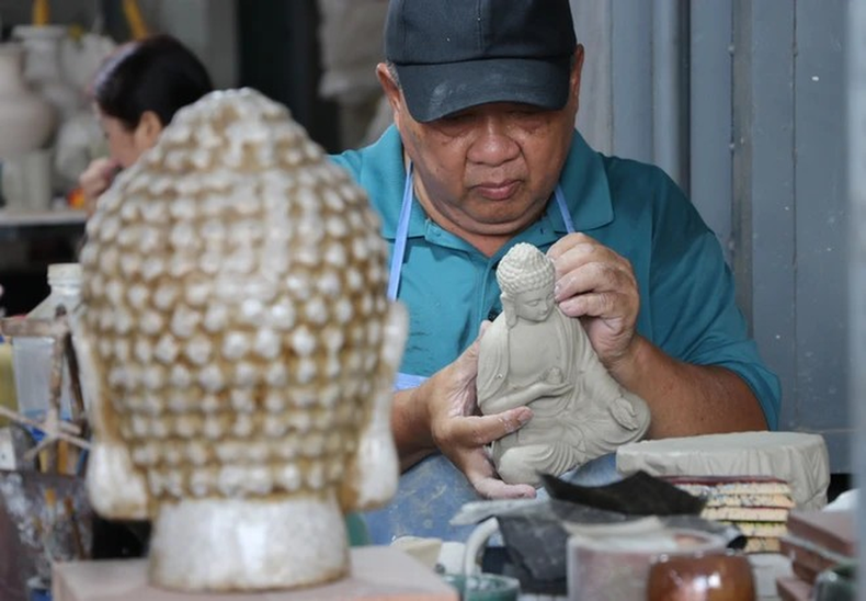 El artista Le Thanh Nhan ha estado involucrado con la cerámica de Bien Hoa durante más de 30 años, elaborando una estatua de Buda de cerámica. El artista Le Thanh Nhan ha estado involucrado con la cerámica de Bien Hoa durante más de 30 años, elaborando una estatua de Buda de cerámica.