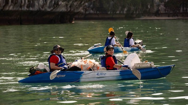 Los voluntarios reman en kayaks para recoger desechos que flotan en el mar.