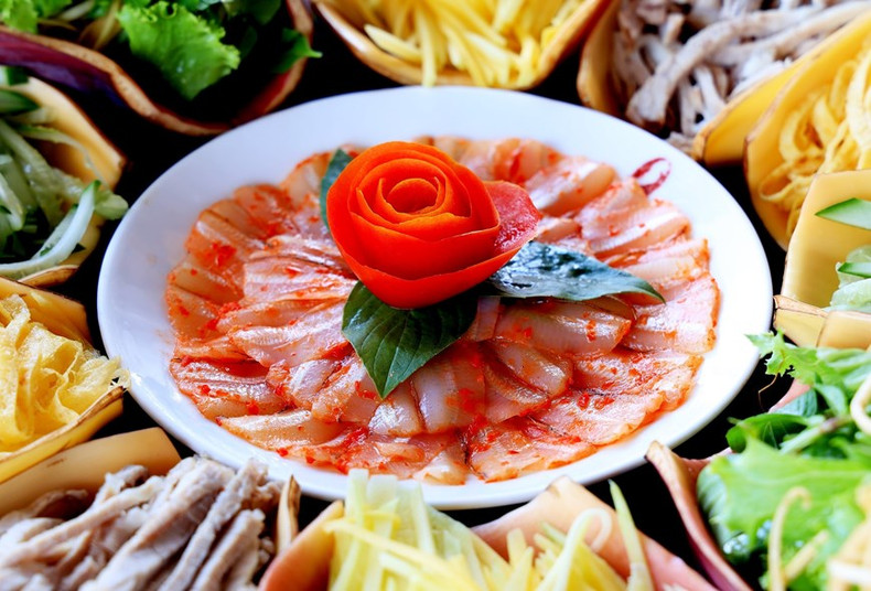 El plato de pescado Mai de color blanco está salpicado de pimientos rojos brillantes y colocados en el medio como "pistilo" El plato de pescado Mai de color blanco está salpicado de pimientos rojos brillantes y colocados en el medio como "pistilo"