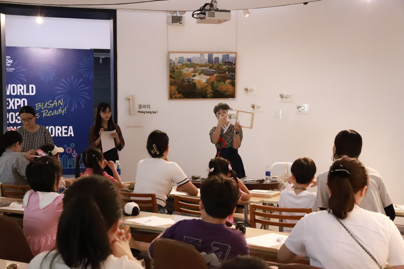 Bajo la instrucción de una maestra surcoreana, las familias participantes aprenden a escribir al estilo caligráfico palabras, frases o una extracción de la letra de su canción favorita. Bajo la instrucción de una maestra surcoreana, las familias participantes aprenden a escribir al estilo caligráfico palabras, frases o una extracción de la letra de su canción favorita.