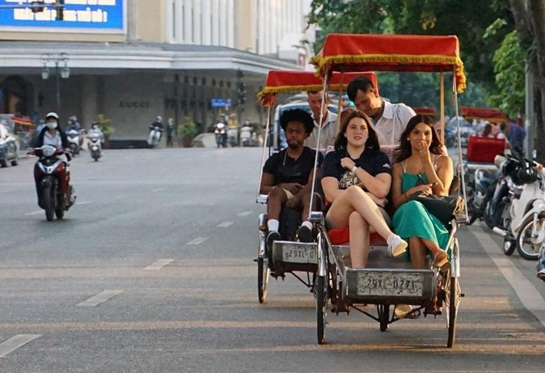 Turistas extranjeros experimentan triciclos alrededor del lago Hoan Kiem.