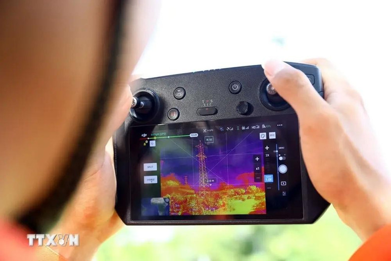 Un trabajador de transmisión eléctrica Binh Dinh utiliza un vehículo aéreo no tripulado (UAV) con una cámara termográfica para verificar la emisión de calor de los equipos en la línea eléctrica. (Fotografía: VNA)
