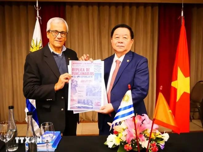 El secretario general del Partido Comunista de Uruguay, Juan Castillo, entrega al jefe de la Comisión de Comunicación y Educación del Comité Central del Partido Comunista de Vietnam, Nguyen Trong Nghia, un artículo sobre la visita del Presidente Ho Chi Minh a Montevideo en 1920, publicado en El Polular, portavoz del Partido Comunista de Uruguay. (Fotografía: VNA)