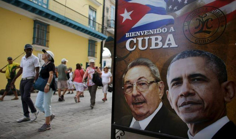 Unos turistas pasan junto un cartel con las efigies del presidente de Estados Unidos, Barack Obama, y de Cuba, Raúl Castro, colocado en la entrada a un restaurante en La Habana, el 17 de marzo de 2016. (Foto: Reuters)