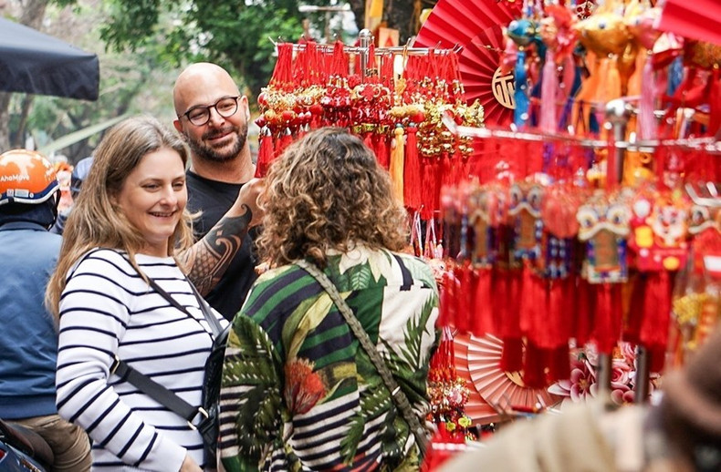 Los turistas extranjeros disfrutan del ambiente alegre en vísperas del Tet en el mercado de flores de Hang Luoc.