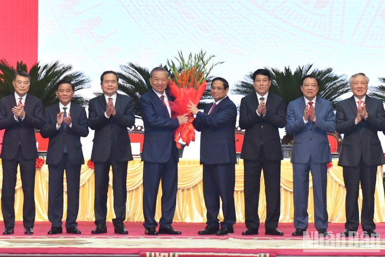 El miembro del Politburó y primer ministro Pham Minh Chinh entrega flores al camarada To Lam en nombre de los dirigentes del Partido y del Estado para felicitarle por su elección como secretario general del PCV del XIII mandato.