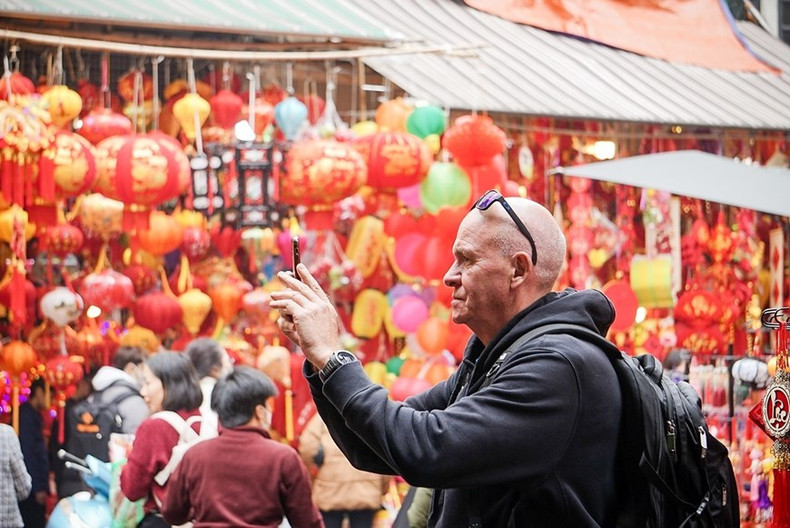 Un turista extranjero toma fotos sobre las preparaciones del Tet de los vietnamitas en el mercado de flores de Hang Luoc.