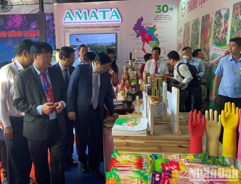 Minh Chinh y otros delegados recorren las zonas expositivas de productos de las provincias y ciudades del Sudeste.