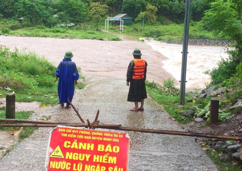 Señal de advertencia de peligro y guardias en un tramo de camino inundado en Quang Tri. (Fotografía: Nhan Dan)