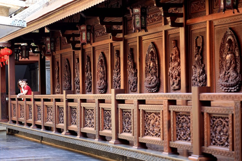 Las paredes y puertas de madera están talladas meticulosamente, con imágenes de budas.