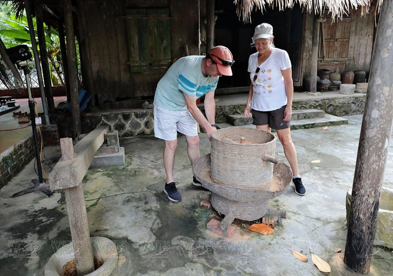 Turistas disfrutan explorando el tradicional molino de arroz. (Fuente: VNA) Turistas disfrutan explorando el tradicional molino de arroz. (Fuente: VNA)