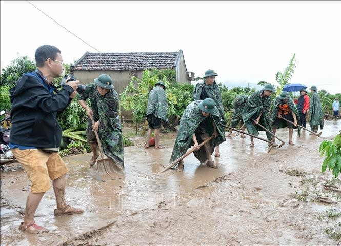 Un reportero de la VNA toma fotos de las actividades de superación de las secuelas de lluvias e innundaciones en la comuna de Tan Lap, distrito de Luc Ngan, provincia norteña de Bac Giang. (Foto: VNA) Un reportero de la VNA toma fotos de las actividades de superación de las secuelas de lluvias e innundaciones en la comuna de Tan Lap, distrito de Luc Ngan, provincia norteña de Bac Giang. (Foto: VNA)