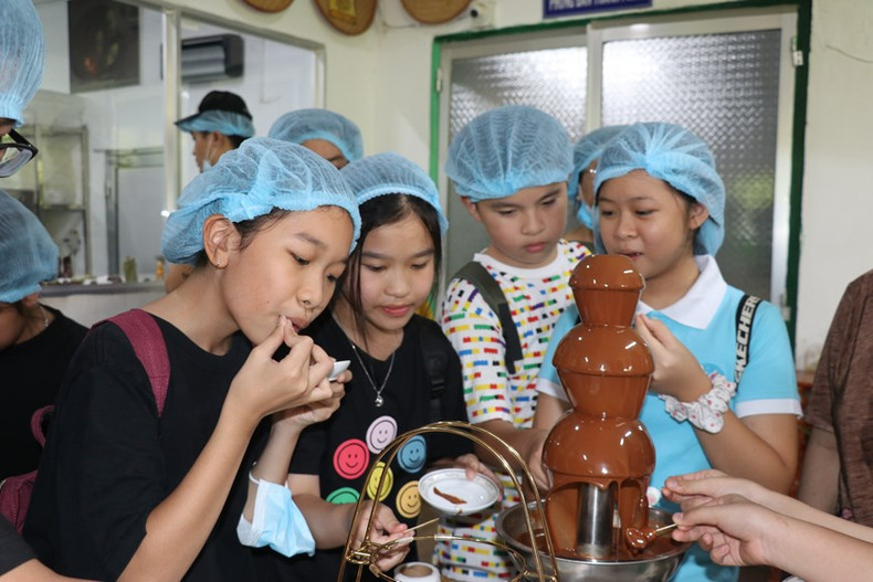 Visitantes disfrutan del chocolate fresco producido en la fábrica. Foto: VNA