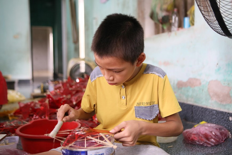 Numerosos niños de la aldea de Bao Dap ayudan a sus padres en la producción de linternas con forma de estrellas durante las vacaciones escolares. (Fuente:VNA)