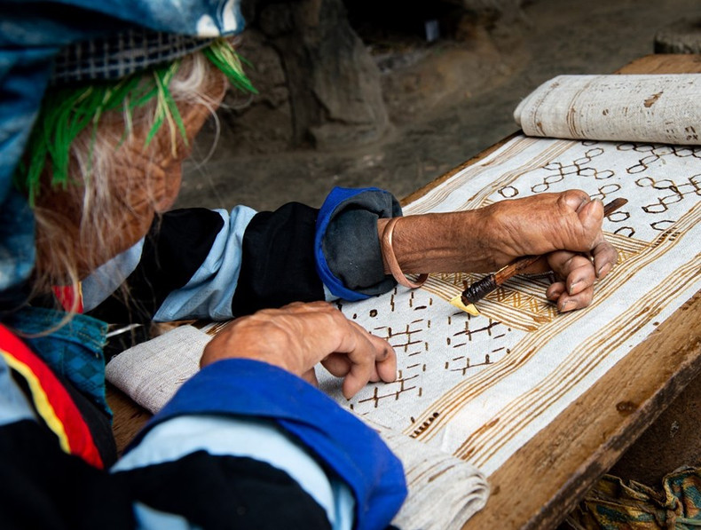 Mujeres de la étnia Mong pintan con cera de abejas sobre lino. (Foto: VNA)