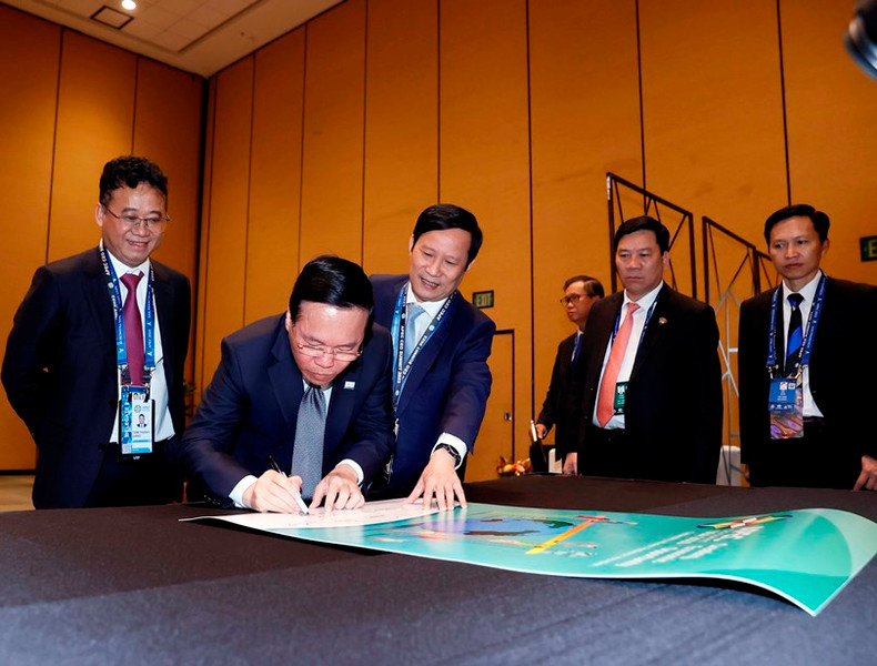 El presidente Vo Van Thuong firma un cartel de recuerdo en la cita.