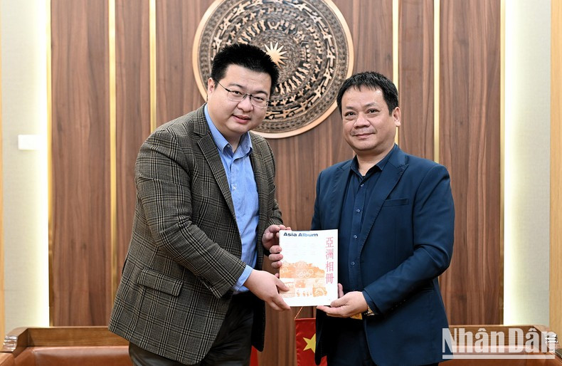 El jefe de la corresponsalía de la agencia de noticias Xinhua en Hanói, Zhouxue Mian, hace entrega de obsequios a Pham Song Ha, miembro del Consejo Editorial del periódico Nhan Dan y jefe del Departamento de Asuntos Político-Diplomáticos.