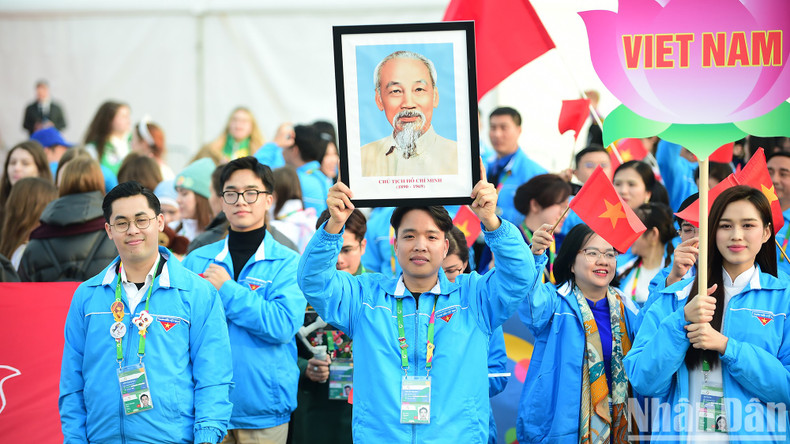 La delegación de Vietnam desfila con la camisa azul que identifica a la Unión de Jóvenes Comunistas Ho Chi Minh, banderas nacionales, foto de Ho Chi Minh y la bandera de la entidad.