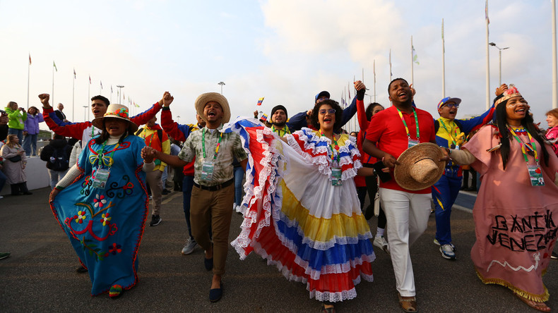 Delegaciones con trajes llamativos marchan con banderas nacionales alrededor del estadio de Sirius.