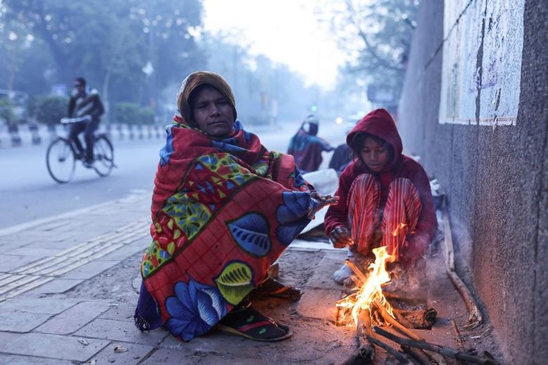 Madre e hija encienden fuego en la acera en una fría mañana invernal en Nueva Delhi, India. La gente en la capital india ha sufrido un fuerte frío por estos días. Madre e hija encienden fuego en la acera en una fría mañana invernal en Nueva Delhi, India. La gente en la capital india ha sufrido un fuerte frío por estos días.