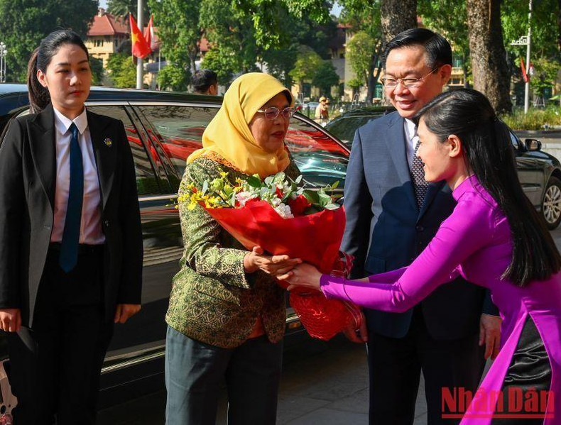 Funcionaria de la Oficina de Asamblea Nacional otorgan flores a Halimah Yacob.
