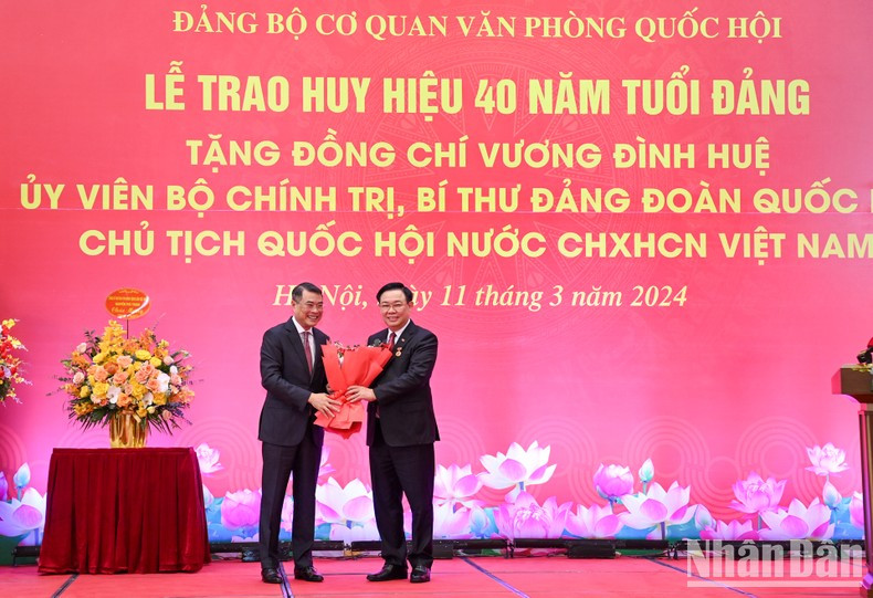 El jefe de la Oficina del Comite Central del PCV, Le Minh Hung, entrega flores para felicitar a Dinh Hue.