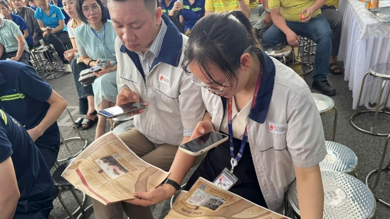 Trabajadores utilizan su teléfono móvil para interactuar con la publicación informativa especial de Nhan Dan. Trabajadores utilizan su teléfono móvil para interactuar con la publicación informativa especial de Nhan Dan.