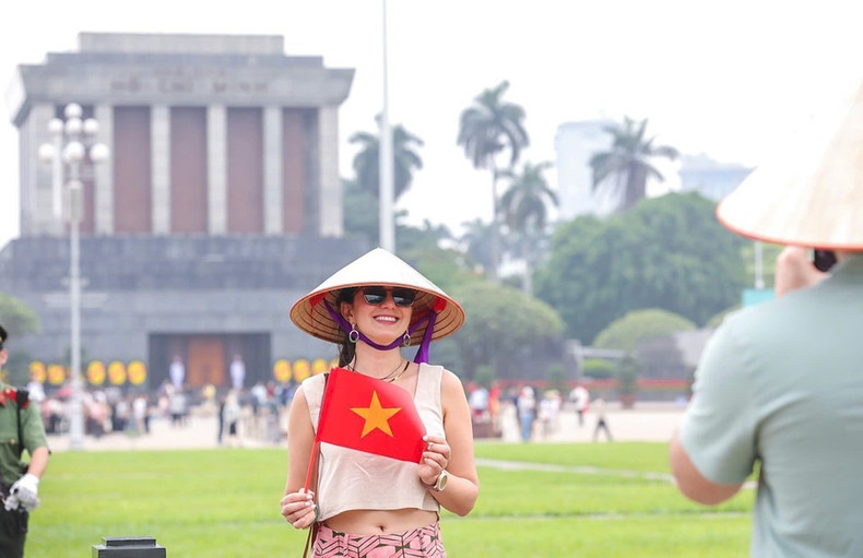 Visitantes extranjeros disfrutan tomándose fotos con la bandera vietnamita. (Foto: VNA) Visitantes extranjeros disfrutan tomándose fotos con la bandera vietnamita. (Foto: VNA)