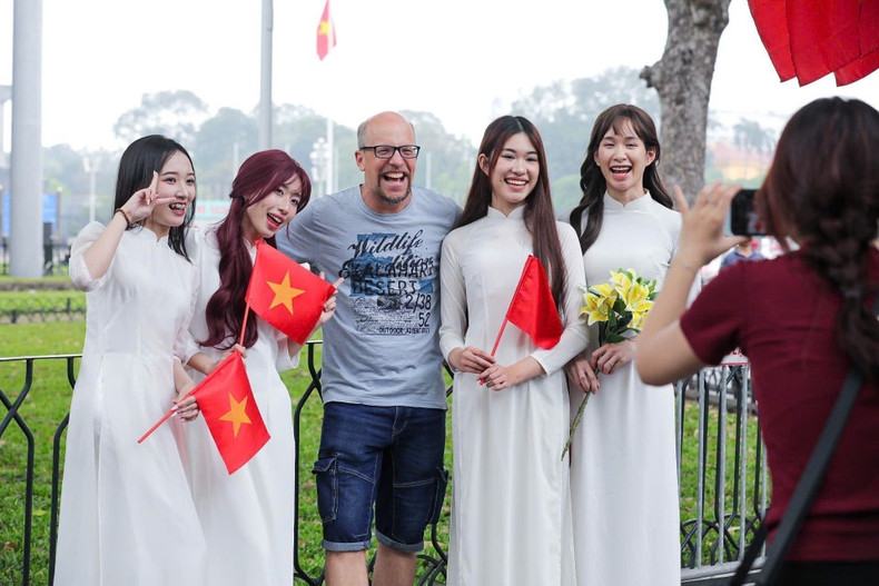 Visitantes extranjeros disfrutan tomándose fotos con la bandera vietnamita. (Foto: VNA) Visitantes extranjeros disfrutan tomándose fotos con la bandera vietnamita. (Foto: VNA)