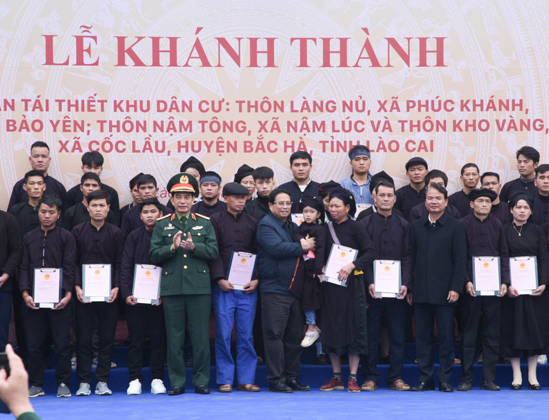 Minh Chinh y los dirigentes locales entregan certificados de derecho de uso de la tierra en nuevas viviendas a las familias de la aldea de Lang Nu.