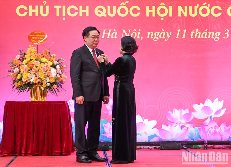 La miembro del Buró Político y permanente del Secretariado del Comité Central del PCV y jefa de su Comisión de Organización, Truong Thi Mai, entrega la insignia a Dinh Hue.