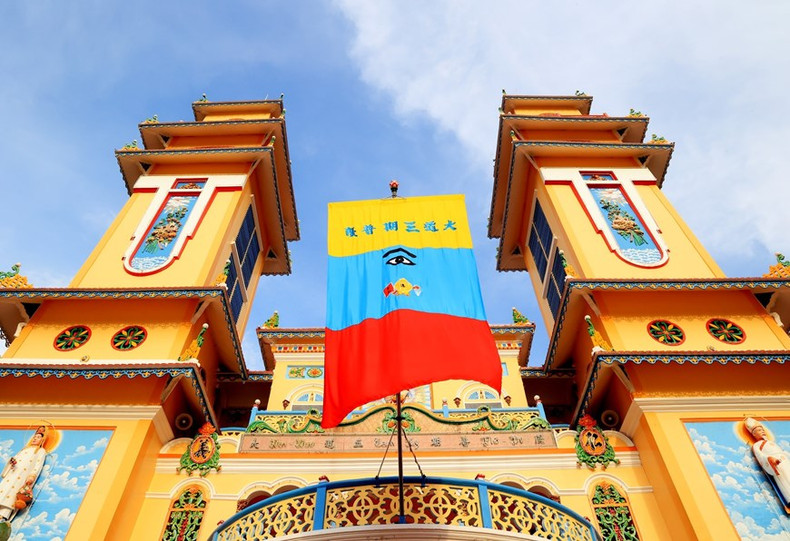 La bandera Cao Dai tiene tres colores: la parte amarilla está bordada con seis palabras en caracteres chinos que identifican el nombre completo de la orden Cao Dai. La parte azul está bordada con el Ojo Divino y los tres dharmas antiguos. La parte inferior es roja y representa el confucianismo mientras que los colores anteriores, amarillo y azul, corresponden al budismo y al taoísmo, respectivamente. (Foto: VNA)