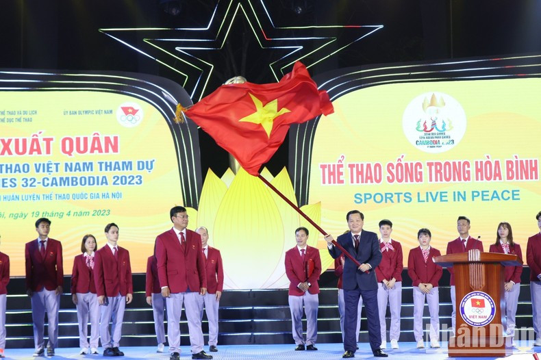 El viceprimer ministro Le Minh Khai agita la bandera de Vietnam antes de entregarla a la delegación deportiva nacional.