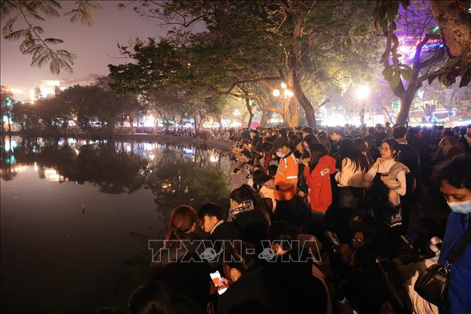 Desde las 9 horas de la noche, mucha gente acude a los espacios peatonales del lago Hoan Kiem para ver el espectáculo de drones y los fuegos artificiales. (Foto: VNA) Desde las 9 horas de la noche, mucha gente acude a los espacios peatonales del lago Hoan Kiem para ver el espectáculo de drones y los fuegos artificiales. (Foto: VNA)