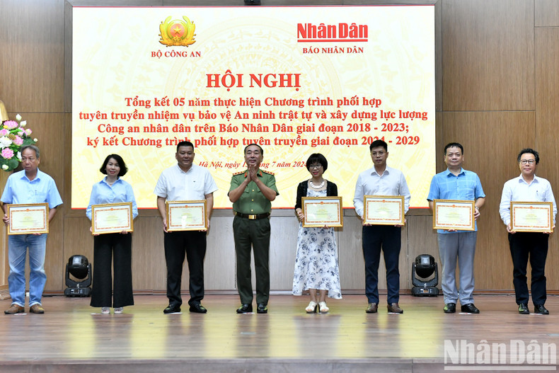 El teniente general Tran Quoc To, viceministro de Seguridad Pública, entrega certificados de mérito de su cartera a los colectivos de Nhan Dan.