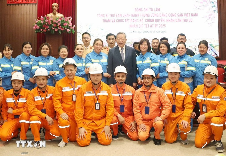 To Lam se toma una foto con ejecutivos y trabajadores de los sectores de electricidad y medio ambiente urbano que están de servicio en la Nochevieja lunar. (Foto: VNA)