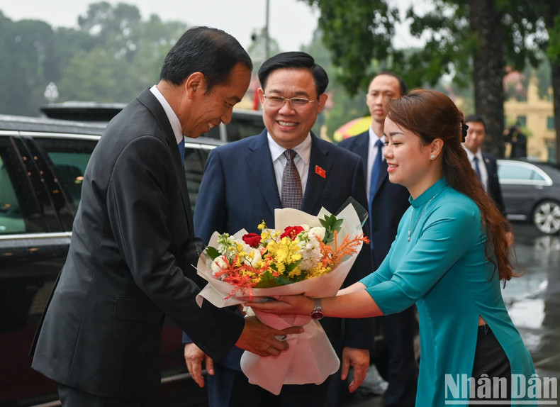 El personal de la Oficina de la ANV entrega flores al presidente de Indonesia, Joko Widodo.