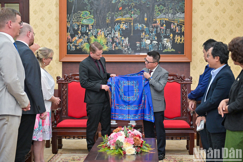 Quoc Minh entrega a la delegación de alto rango del Partido de Izquierda de Alemania un pañuelo de seda, producto de Nhan Dan.